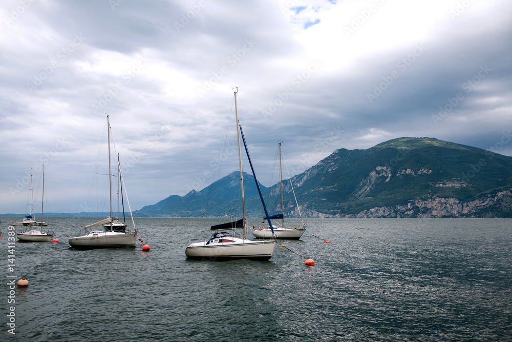 moored yachts on the smooth surface of lake Garda in the early morning, Italy