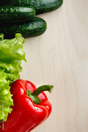 Fresh vegetables on the table: red pepper, lettuce, cucumber. Cutting board