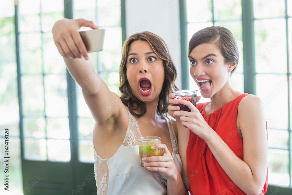 Friends taking a selfie while holding cocktail glasses Friends taking a selfie while holding cocktail glasses