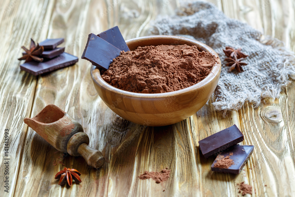 Fotografie Cocoa powder and chocolate in a wooden bowl.