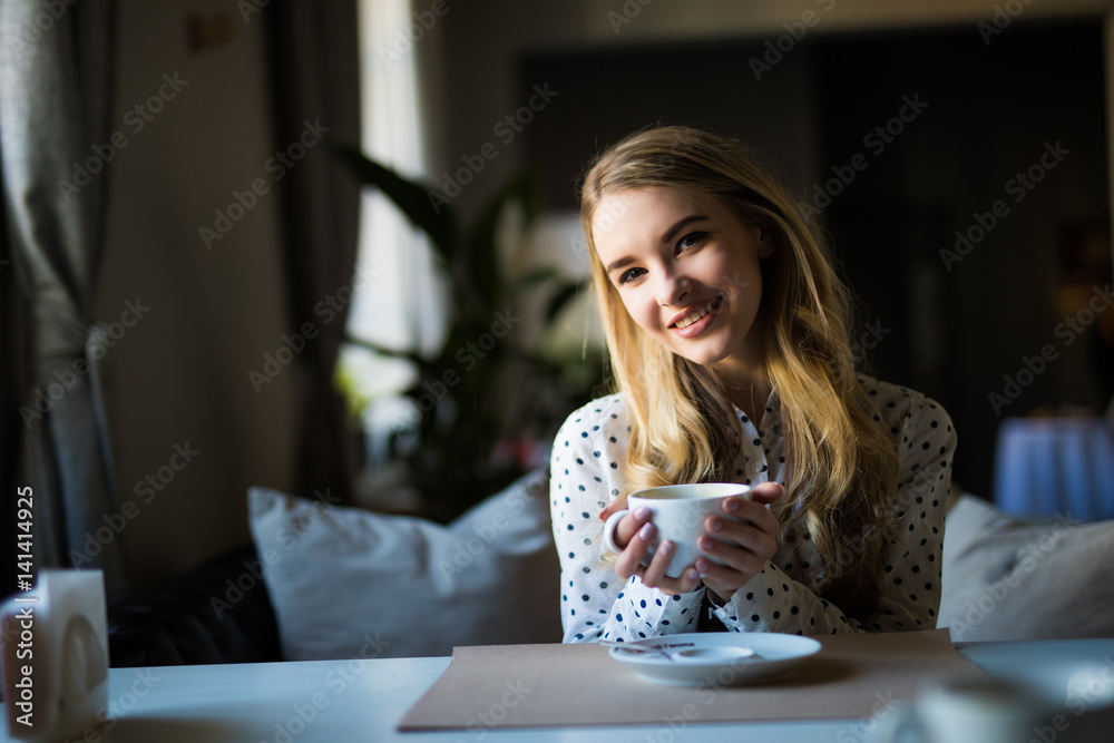 pretty young woman sitting in the cafe with a cup of or coffee pretty young woman sitting in the cafe with a cup of or coffee
