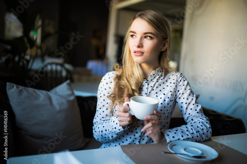 Young blond woman enjoying coffee time in cafe