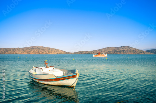 Summertime Background. Traditional wooden fishing boat at Elounda, Crete, Greece. © gatsi