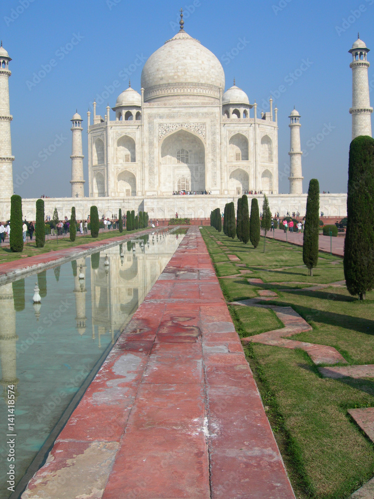 Obraz premium Side perspective of the Taj Mahal mausoleum in Agra, India, with the main building dome framed by the minaret towers and the reflection pool.