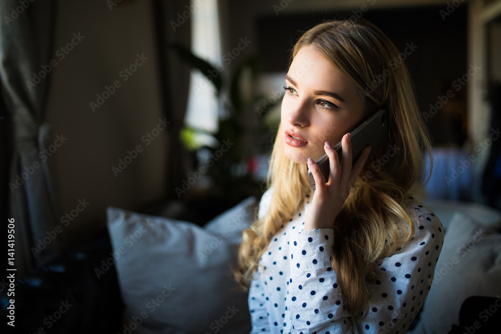 Young woman talking on mobile phone and drinking coffee at the table in cafe Young woman talking on mobile phone and drinking coffee at the table in cafe