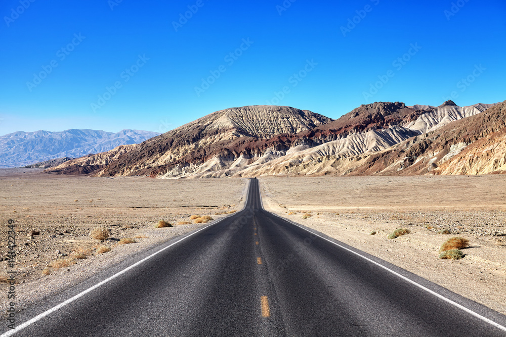 Desert road towards mountain range at Death Valley, travel concept, focus on mountains, USA.