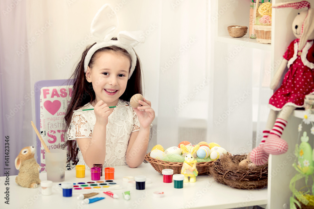 Happy easter! A beautiful child girl painting Easter eggs. Happy family preparing for Easter. Cute little child girl wearing bunny ears on Easter day. Happy easter! A beautiful child girl painting Easter eggs. Happy family preparing for Easter. Cute little child girl wearing bunny ears on Easter day.