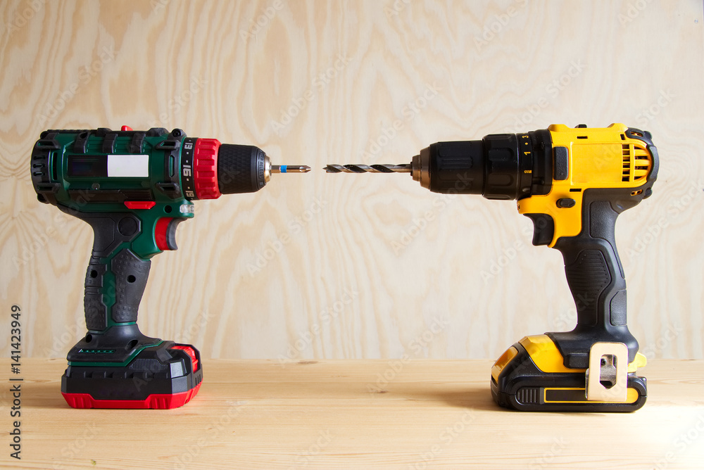 electric screwdriver and cordless drill against wooden background,  rechargeable drill and screwdriver, modern electric tools for tradesmen  Stock Photo | Adobe Stock