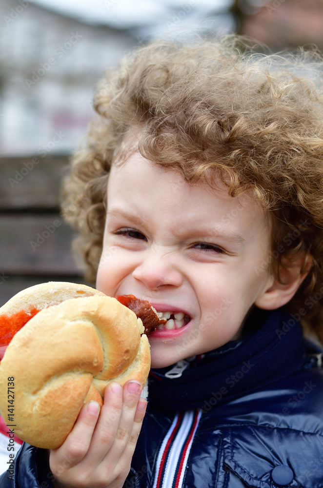 Kind isst Rostbratwurst im Brötchen mit Ketchup Kind isst Rostbratwurst im Brötchen mit Ketchup