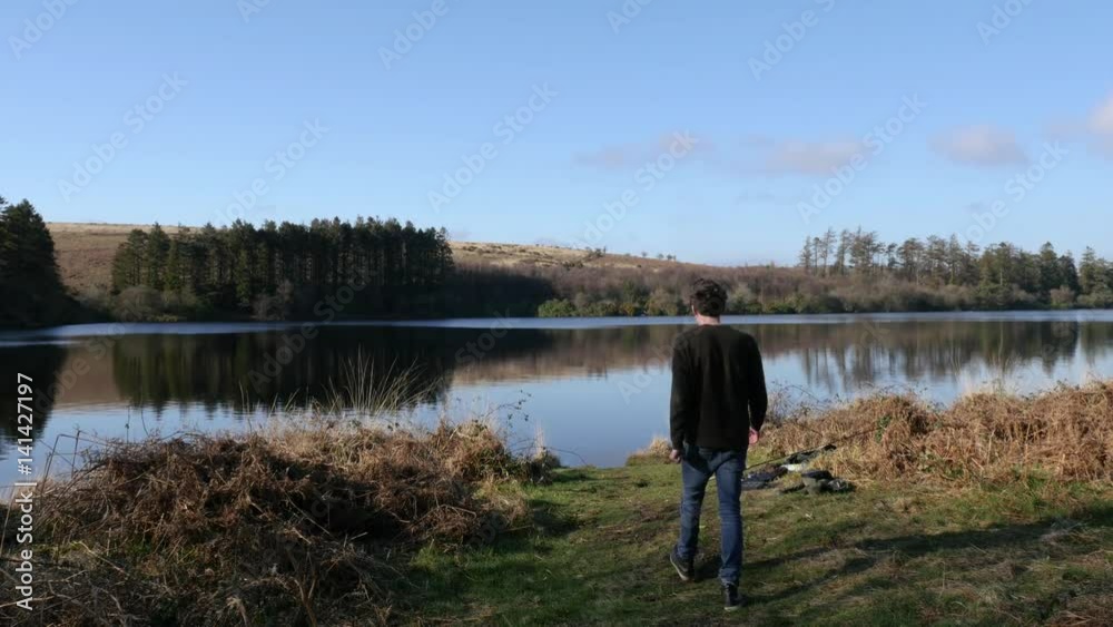 Man walks towards a lake and admires the view Man walks towards a lake and admires the view