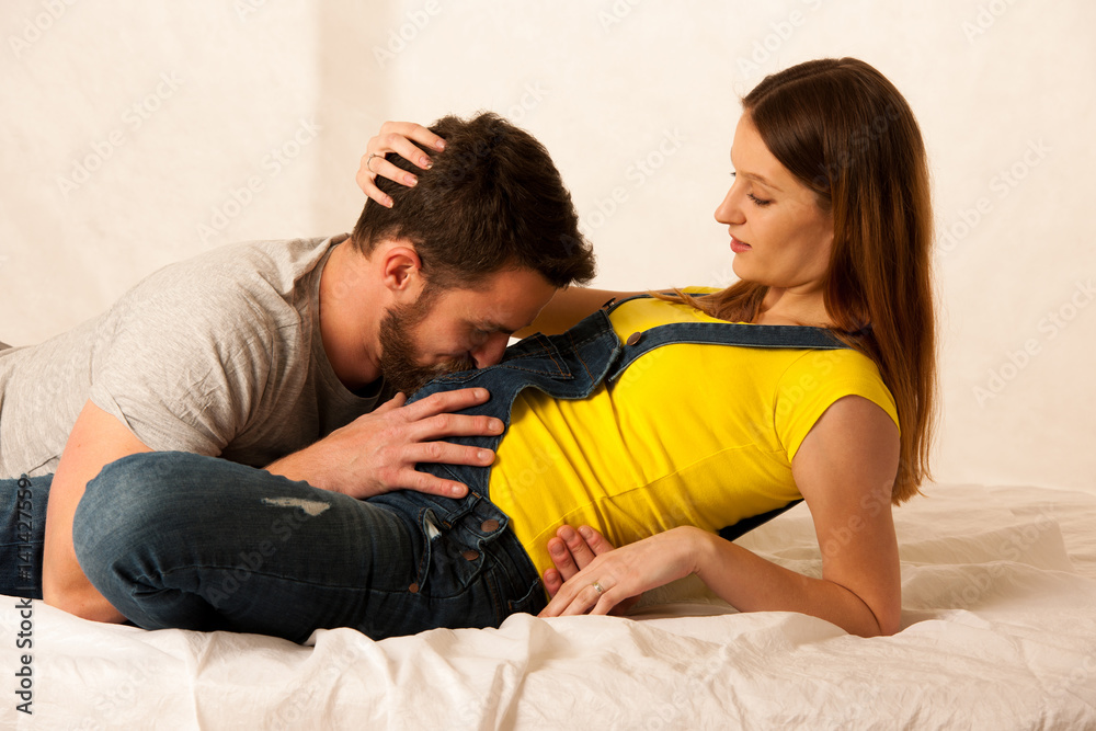 Beautiful coule - young man and pregnant woman resting on bed Beautiful coule - young man and pregnant woman resting on bed