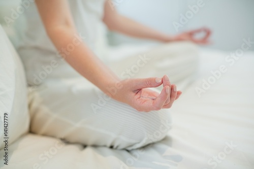 Woman doing meditation on bed in bedroom