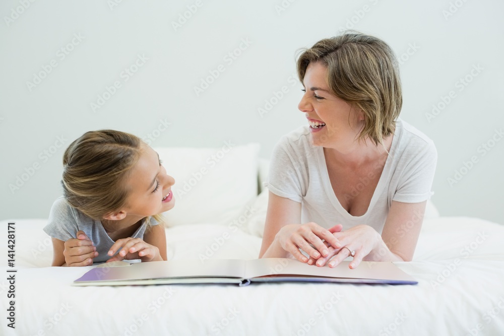 Mother and daughter lying on bed and reading book Mother and daughter lying on bed and reading book