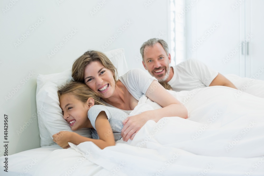 Fototapeta premium Happy family lying together on bed in bedroom at home