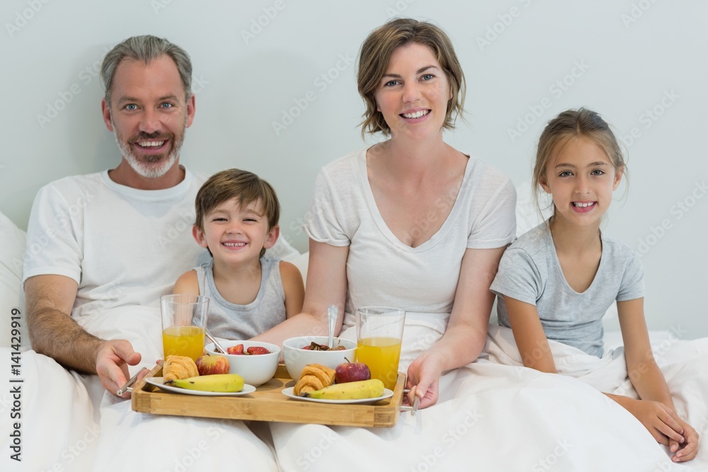 Portrait of smiling family having breakfast on bed in bedroom Portrait of smiling family having breakfast on bed in bedroom