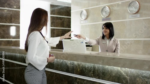 young woman gets a key in hotel for room