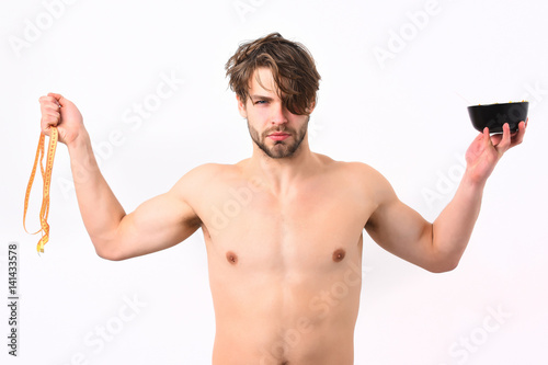 Caucasian macho holding black bowl with pasta and measuring tape