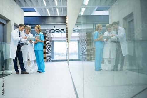 Medical team discussing over digital tablet in corridor