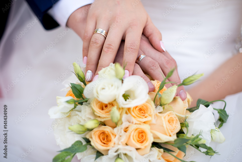 Hands and rings on wedding bouquet