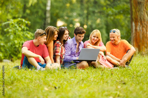 a group of students with laptop relaxing in the Park on a Sunny 