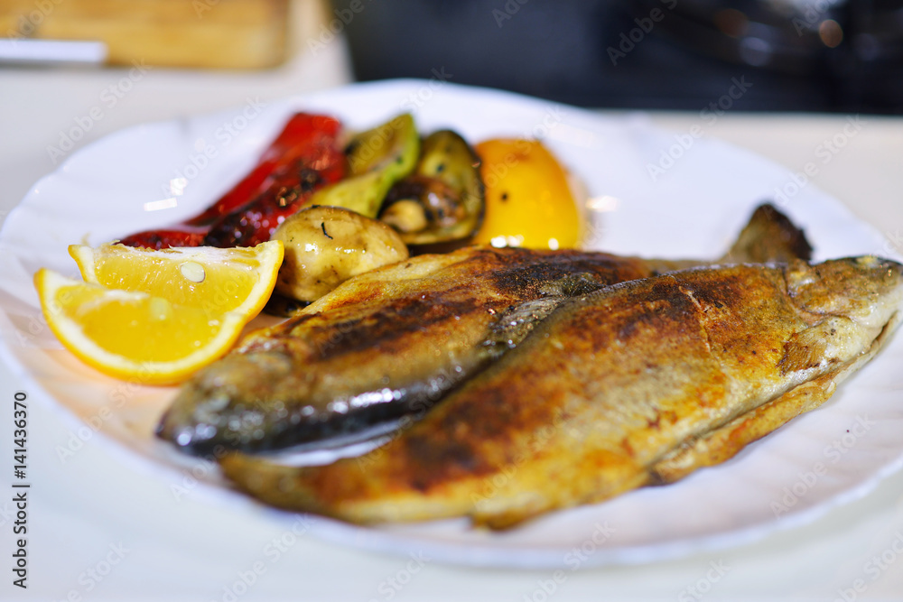 Tasty baked fish on plate on table close-up Tasty baked fish on plate on table close-up