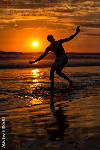 Silhouette of young male capoeira dancer  yoga and martial art specialist at beach in Mexico during spectacular sunset