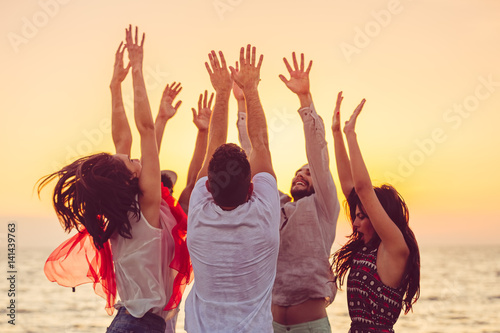 people dancing at the beach with hands up. concept about party, music and people photo