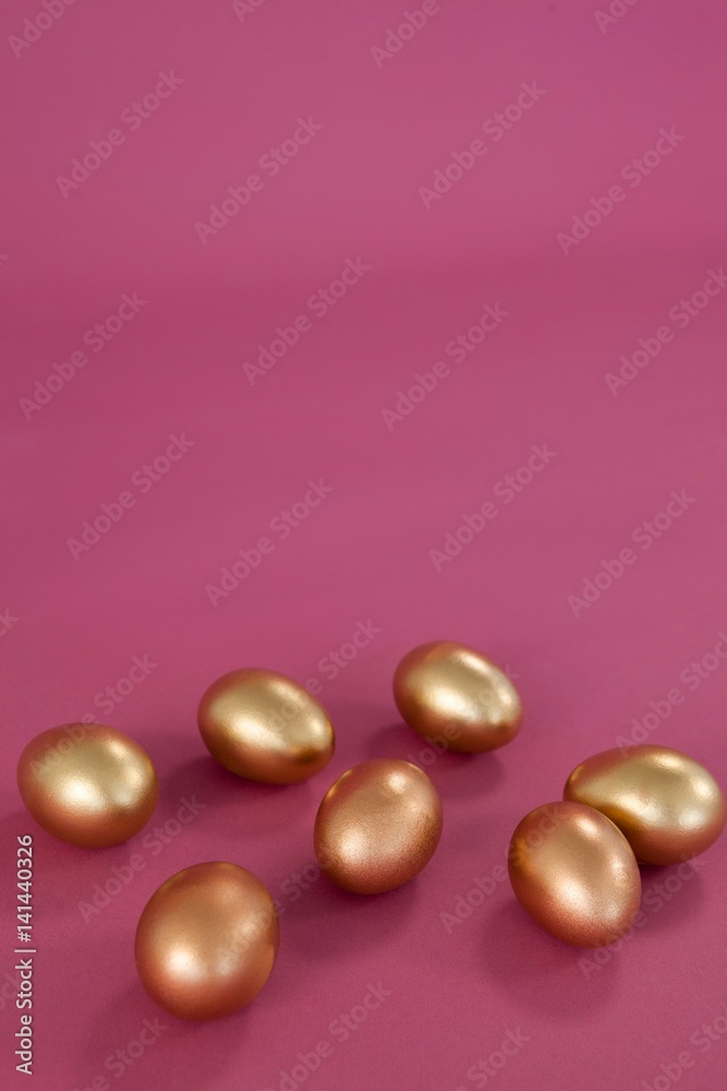Golden Easter eggs on pink background