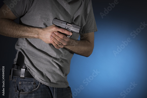 Man drawing a concealed carry pistol from a holster