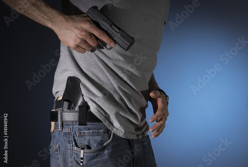 Man drawing a concealed carry pistol from a holster photo