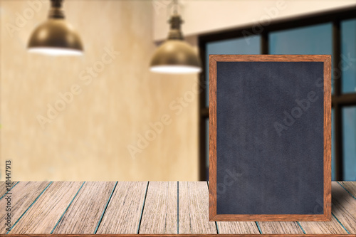 Chalkboard wood frame blackboard sign menu on wooden table, Blurred image background, Template mock up for adding your design and leave space beside frame for adding more text.