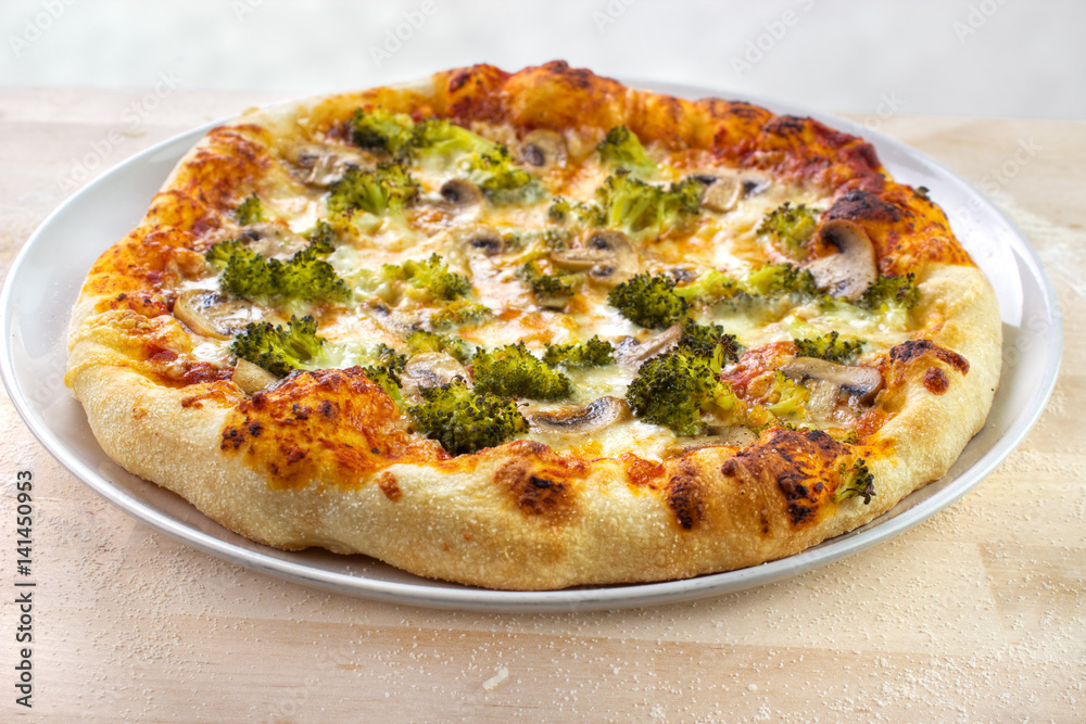 Home baked pizza with broccoli , mushrooms and mozzarella cheese on wooden baking board Home baked pizza with broccoli , mushrooms and mozzarella cheese on wooden baking board