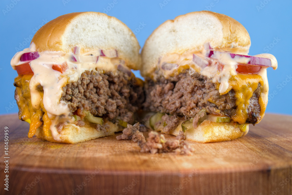 Burger with big patty , real cheddar , tomato , pickels , red onion and sauce , cut in half