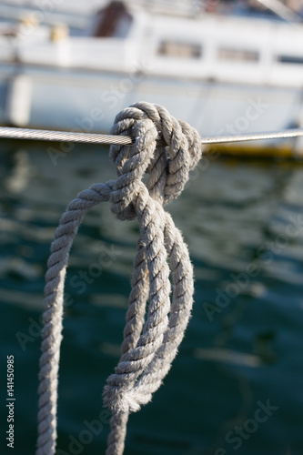 White rope, canat knotted in a knot hanging on a board yacht, sailboat