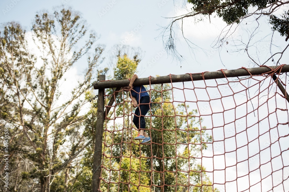 Obraz premium Fit woman climbing a net during obstacle course