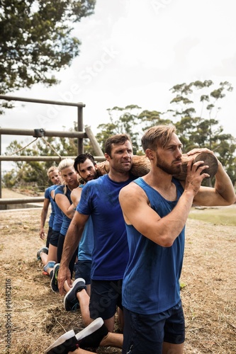 People holding a heavy wooden log during boot camp