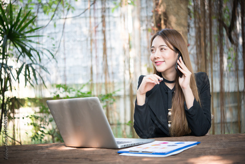 Young business woman talking on the phone while sitting at her working place.