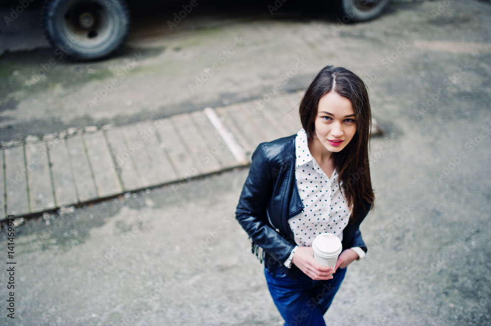 Portrait of stylish young girl wear on leather jacket and ripped jeans with cup of coffee. Street fashion model style. Portrait of stylish young girl wear on leather jacket and ripped jeans with cup of coffee. Street fashion model style.