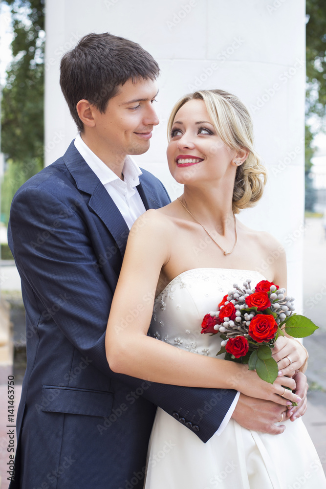 Young couple in wedding gown. Bride holding bouquet of flowers Young couple in wedding gown. Bride holding bouquet of flowers