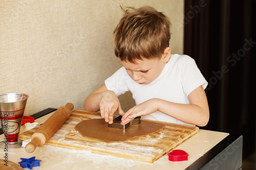 Children's hands make gingerbread. Small boy cutting cookies for Christmas. Kid Baking Cooking Cookies Fun Concept