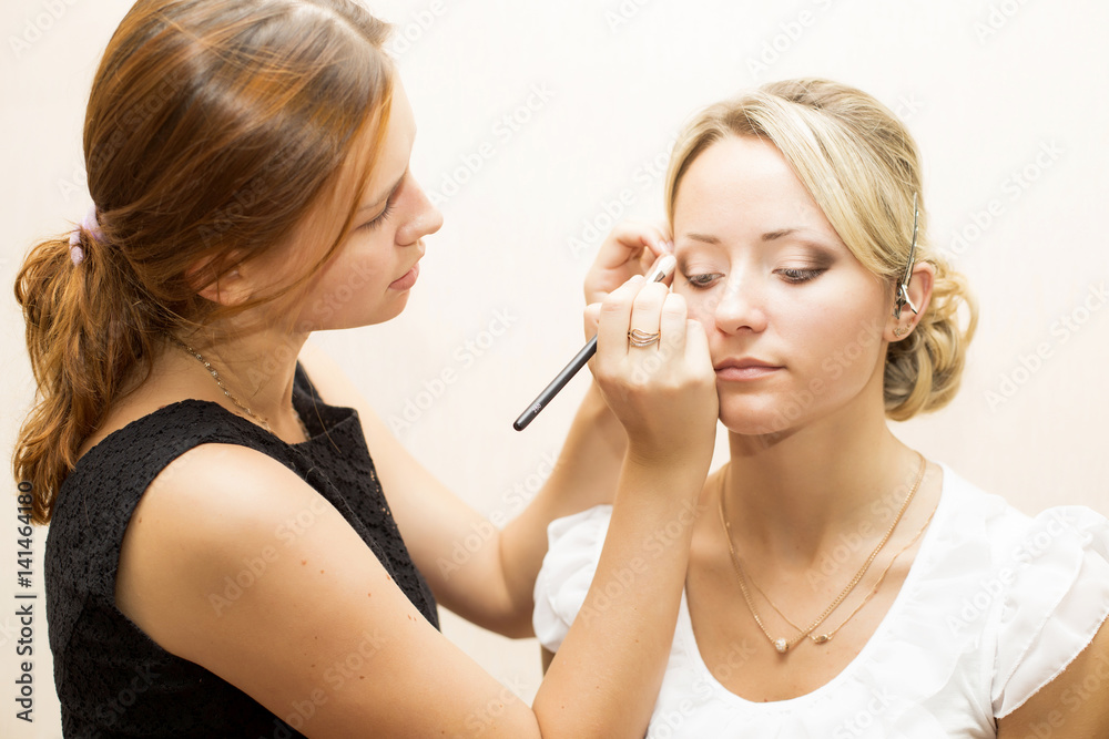 Woman applying make up for a bride in her wedding day near mirror Woman applying make up for a bride in her wedding day near mirror