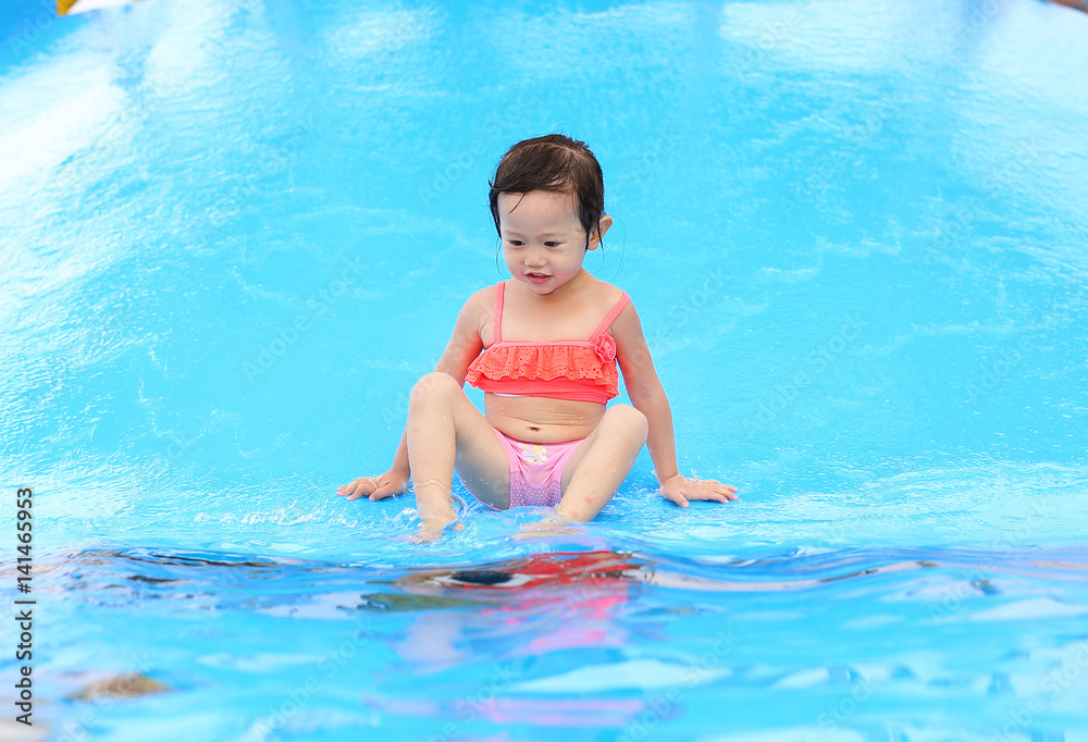 Pretty little girl playing in swimming pool outdoors