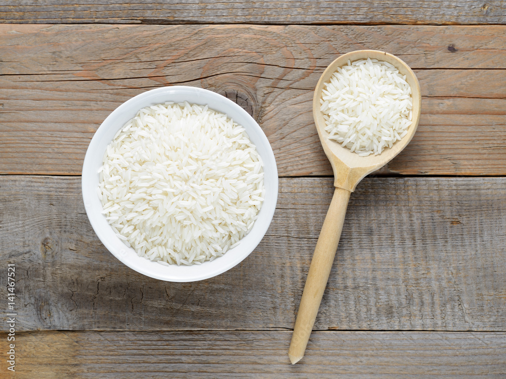 Jasmine rice in bowl and spoon on wooden table Jasmine rice in bowl and spoon on wooden table