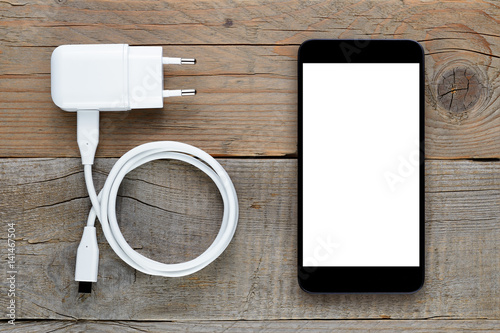 Smartphone and charger on wooden table photo