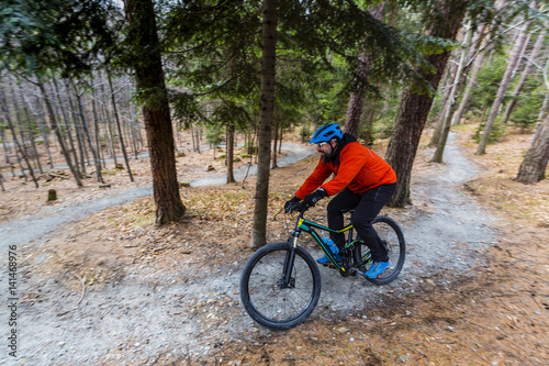 Mountain biker riding on bike in early spring mountains forest landscape. Man cycling MTB enduro flow trail track. Outdoor sport activity.
