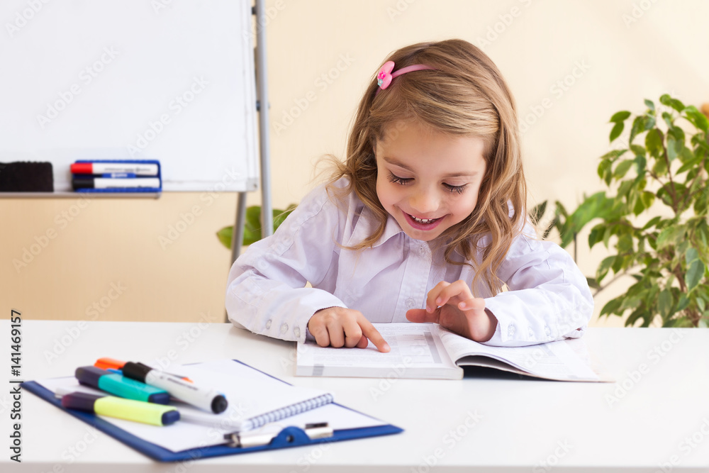 Beautiful little girl reads sitting at table Beautiful little girl reads sitting at table