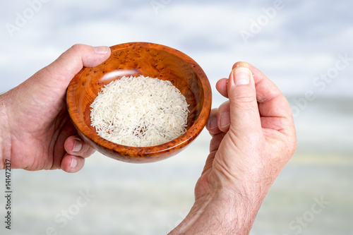 Hand holding wooden bowl with rice