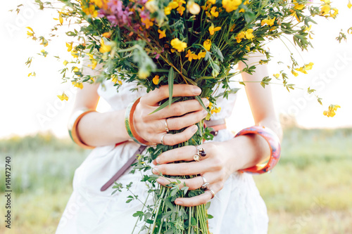.A hippy girl holding a bouquet of wildflowers in her hands