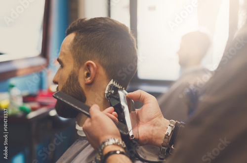 Fotografie Man getting haircut by hairstylist at barbershop