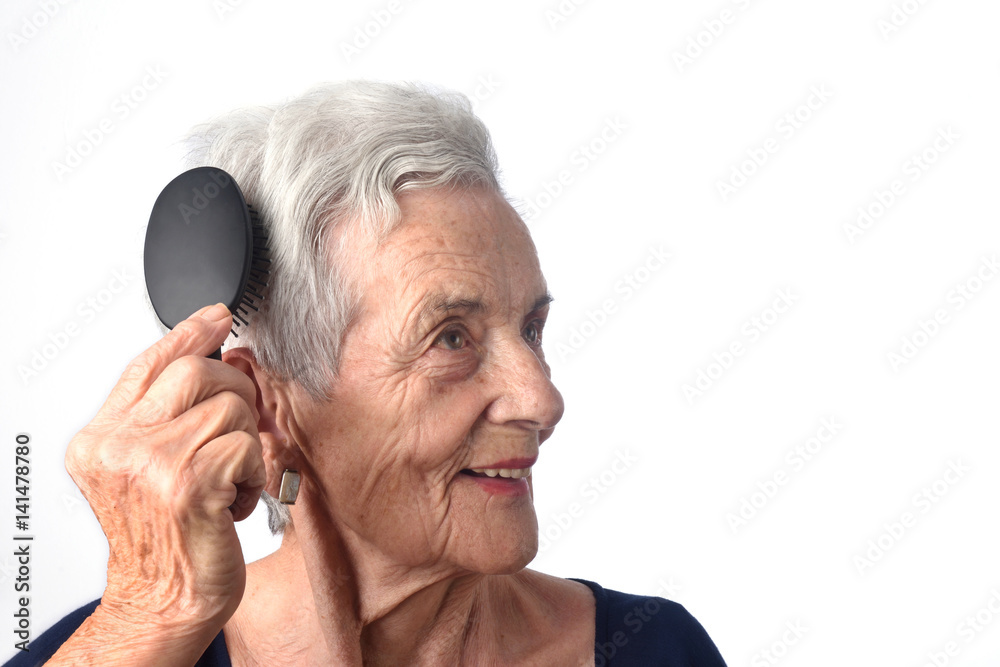 Senior woman combing her hair on white background Senior woman combing her hair on white background